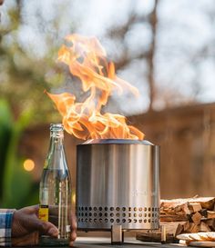 a person sitting at a table with a beer and fire in front of it,