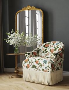 a chair with a flowered upholstered back and fringe trim around the legs