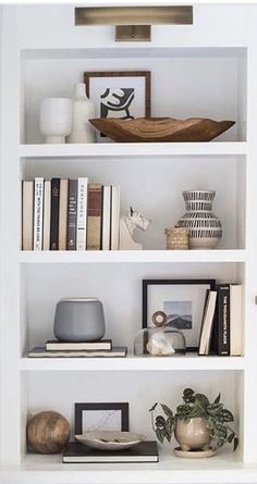 an open book shelf with books and other items on it, including vases and candles