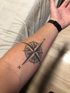 a man's arm with a compass tattoo on it