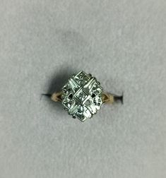 an old diamond ring sitting on top of a gray surface with the center stone missing