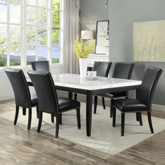 a dining room table with black chairs and a white marble top in front of a window