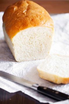 a loaf of white bread sitting next to a knife