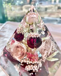 a glass pyramid with flowers and pearls on it