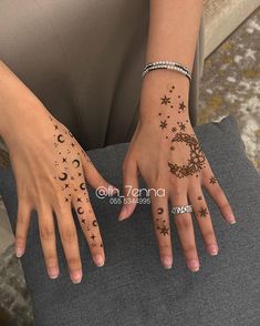 a woman's hands with tattoos on their fingers and wrist, both showing the moon and stars