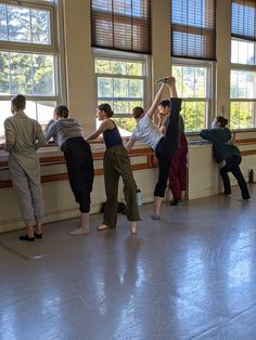 a group of people standing in front of windows with their arms up and feet on the ground