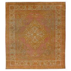 an orange and gold rug with ornate designs on the center, in front of a white background