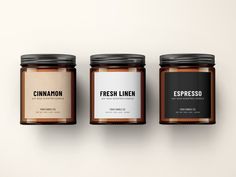 three jars with labels on them sitting side by side in front of a white wall