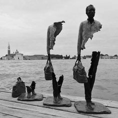 two statues are standing on the edge of a pier with their feet in the air