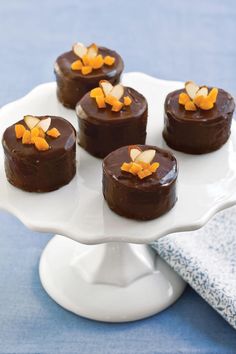 small chocolate cakes on a white plate with orange peels in the top and bottom