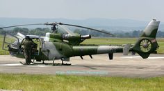 a helicopter sitting on top of an airport tarmac next to a grass covered field