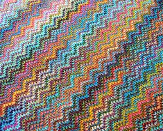 a multicolored crocheted blanket is laying on the ground