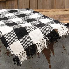 a black and white checkered blanket sitting on top of a wooden bench next to a wall