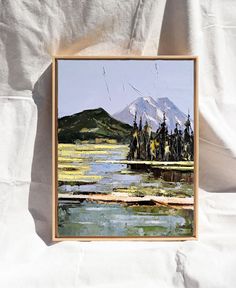 a painting on a white sheet with a mountain in the background and water running through it