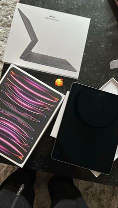 an open laptop computer sitting on top of a table next to a box and papers