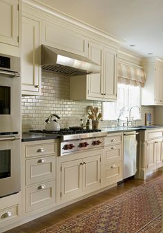 a large kitchen with white cabinets and stainless steel appliances