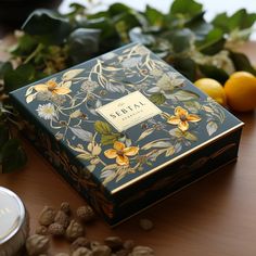 the box is next to some lemons and other fruits on a table with leaves