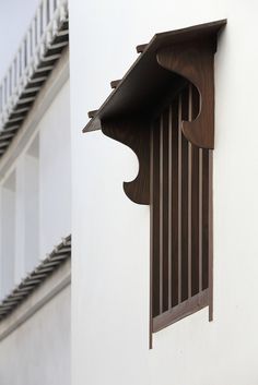 a wooden window frame on the side of a white building with balconies and railings