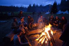 a group of people sitting around a campfire