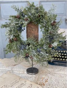 a christmas wreath sitting on top of a table next to an old book and typewriter