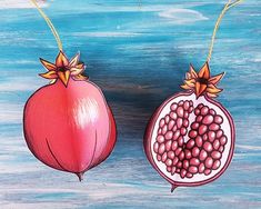 two pomegranates are hanging from strings on a blue wooden table top