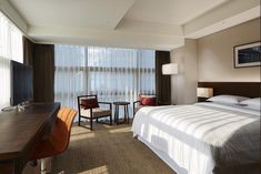 a hotel room with a bed, desk and television