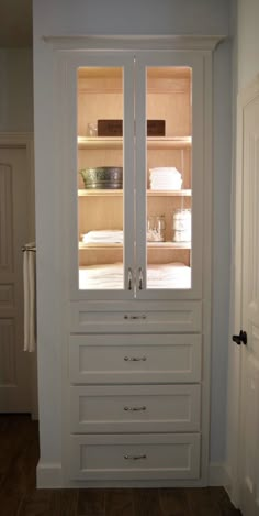 a white closet with glass doors and drawers