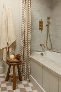 a bathroom with a checkered floor and white walls, two towels hanging on the bathtub