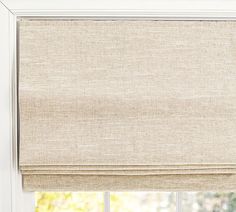 an open window with a beige roman blind