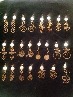 many different types of earrings are displayed on a black surface with white beads and gold spirals