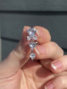 a woman's hand holding a ring with three diamonds on it and two fingers