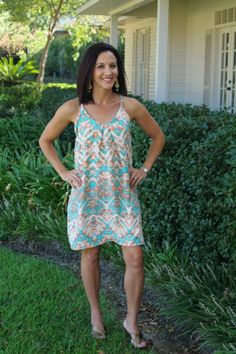 a woman standing in front of a house with her hands on her hips and smiling