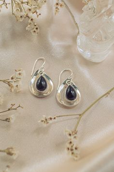 Elegant teardrop Black Onyx embraced in sterling silver frames make our Aura Drops earrings a subtle, refined addition to your outfit. Their graceful sway adds a playful mystique and shows off your unique, feminine style. Authentic Sivalya Black Onyx Black Onyx: Endurance, Perseverance, Grounding Hallmarked Metal: 925 Sterling Silver Gemstone Size: 10mm x 7mm Cut: Pear Shaped Cabochons Polished Sterling Silver Teardrop Earrings, Sterling Silver Teardrop Earrings With Polished Finish, Black Teardrop Gemstone Earrings, Sterling Silver Teardrop Pendant Earrings For Party, Black Teardrop Sterling Silver Earrings, Silver Onyx Teardrop Earrings, Black Sterling Silver Teardrop Earrings, Sterling Silver Teardrop Crown Earrings For Gift, Sterling Silver Gemstone Teardrop Earrings