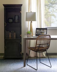 a chair sitting in front of a book shelf next to a table with a lamp on it