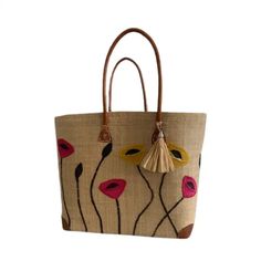 a handbag with flowers painted on the side and tassels hanging from it