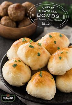 small rolls on a black plate next to some meatballs and parsley in a bowl