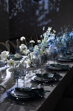 the table is set with blue and white flowers in vases, silverware, and napkins