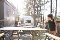 a woman standing next to a table with a camper in the background