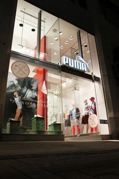 a store front with mannequins in the window and an advertisement for puma