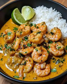 a bowl filled with shrimp and rice next to a lime wedge on top of a wooden table