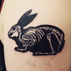 a skeleton rabbit tattoo on the back of a woman's arm