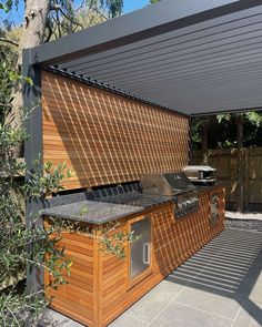 an outdoor bbq and grill area under a pergolated roof