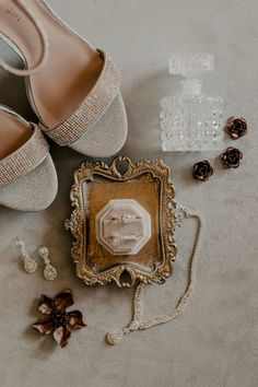 wedding shoes and jewelry laid out on the floor next to an empty glass box with a ring in it