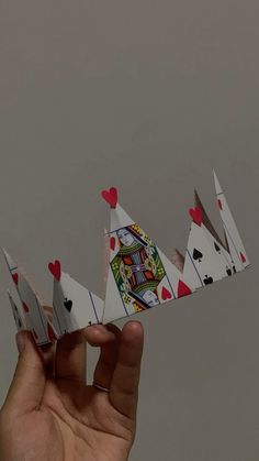 a hand holding four playing cards in the shape of a boat with hearts on it