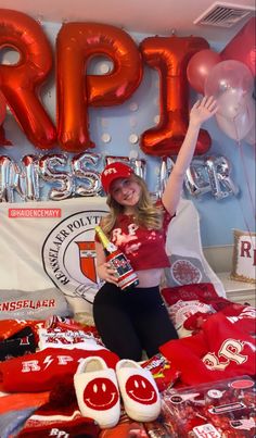 a woman sitting on top of a bed in front of balloons and t - shirts