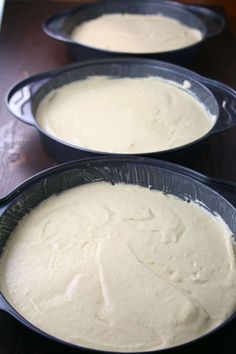 three black pans filled with batter sitting on top of a wooden table next to each other