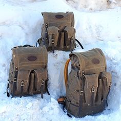 three backpacks sitting in the snow on top of it's side and one is empty