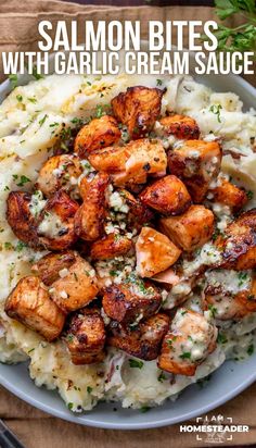 salmon bites with garlic cream sauce on top of mashed potatoes in a white bowl