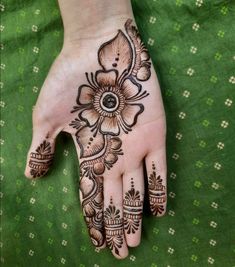 a henna tattoo on the palm of someone's hand with flowers and leaves