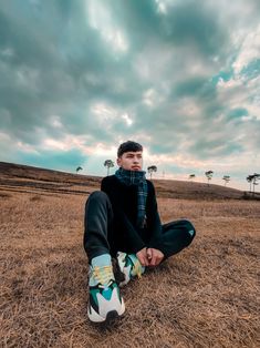 a young man sitting on the ground with his feet up in the air while wearing sneakers